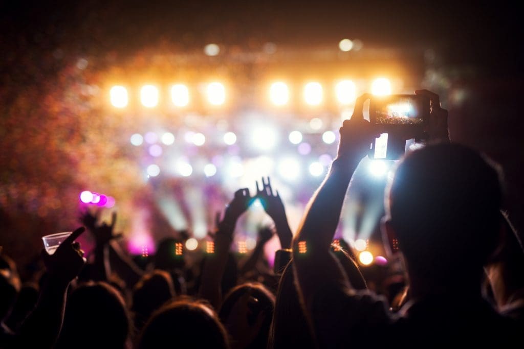 People at a concert capturing moments on their phones, immersed in the vibrant atmosphere of live music.