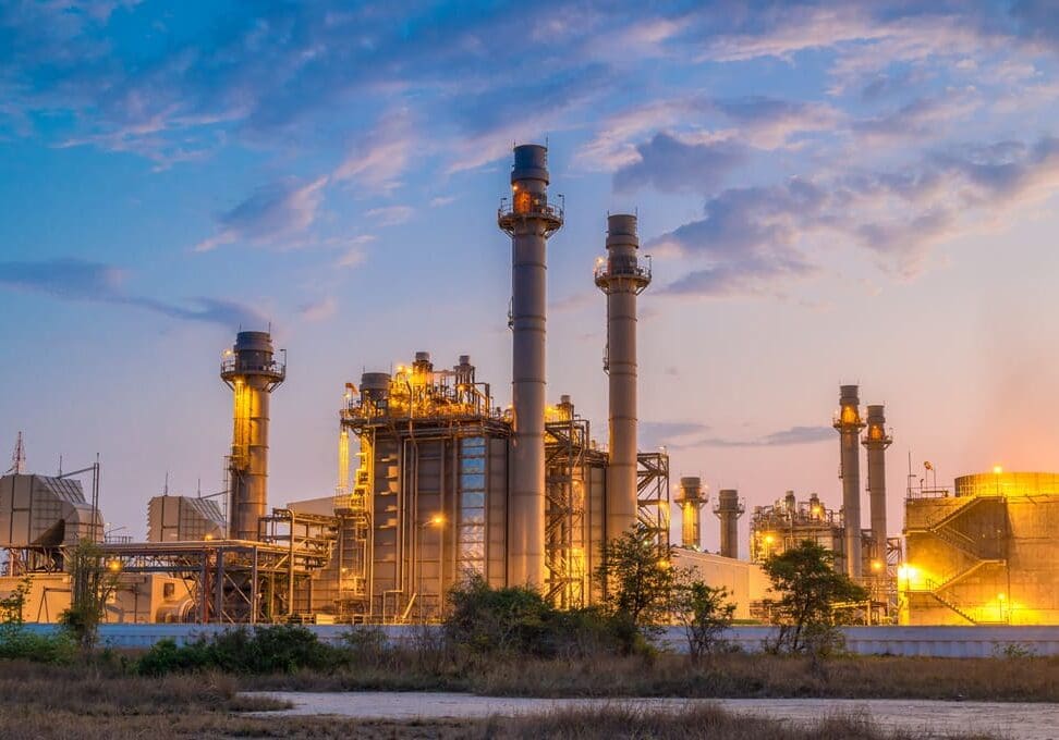 A sprawling industrial plant at dusk, set against a serene blue sky.