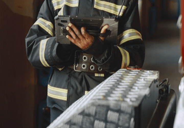 A fire fighter holding a tablet, possibly using it for emergency response coordination or accessing critical information.