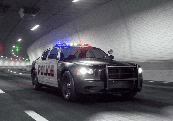 A police car speeding through a dark tunnel at night, its flashing lights illuminating the surroundings.