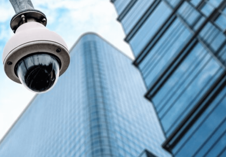 A security camera in front of a tall building, monitoring the surroundings for enhanced safety.